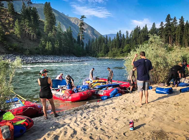People on a sandy beach unloading equipment from a boat on the Main Salmon River in Idaho.