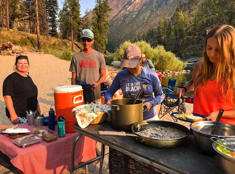 Group eating a catered dinner during a Main Salmon River River whitewater rafting vacation in Idaho.