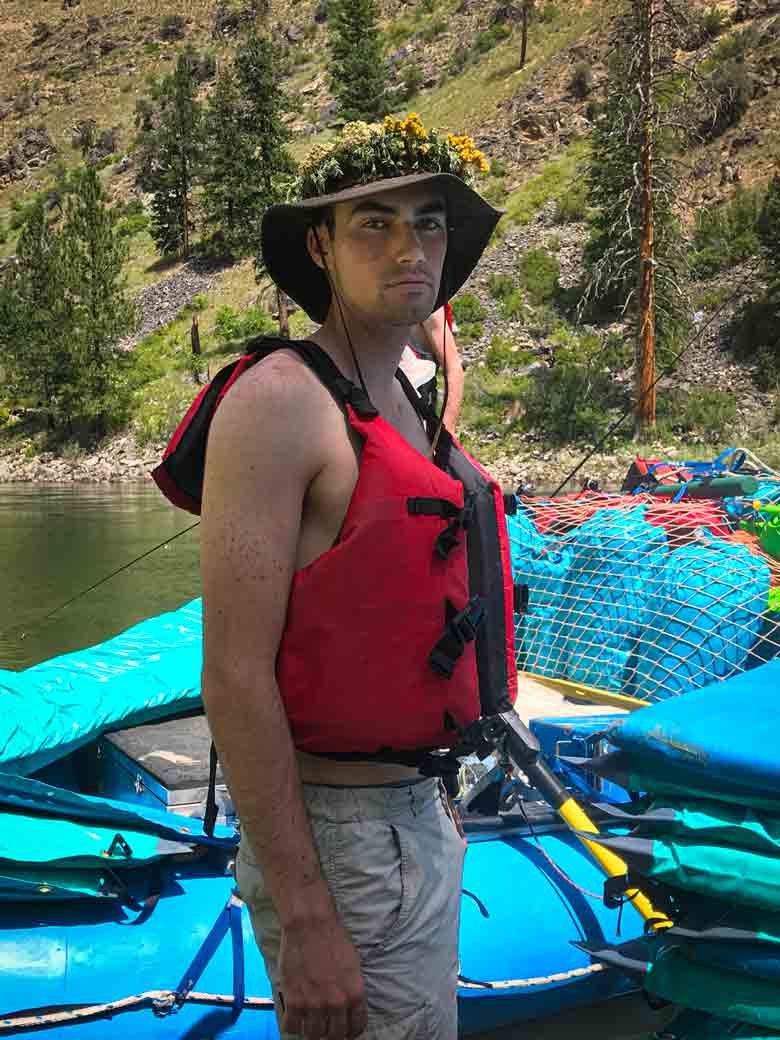 River guide on the Main Salmon River looking serious while he wears a wreath of flowers on his hat.